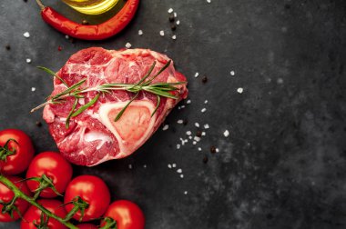 raw beef steak with tomatoes and spices on a stone background.