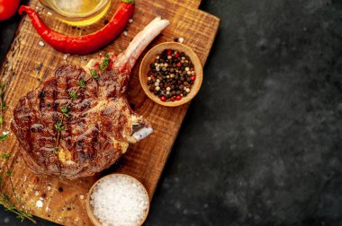 steak - grilled beef tomahawk with spices, thyme on a stone background
