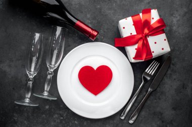 Sevgililer Günü için masa ayarlama - beyaz tabak, şarap, hediye, mutfak aletleri, taş zeminde kalpler