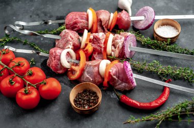 Çiğ et şişlerinin açılı görüntüsü. Arka planda sebzeli ve baharatlı ızgara et..