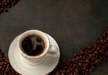 Angle  view of cup of tasty coffee and beans on a stone background. 