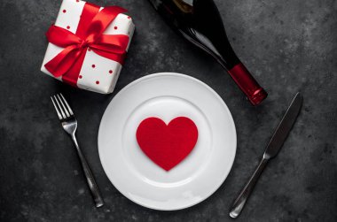 Sevgililer Günü için en iyi masa manzarası - beyaz tabak, şarap, hediye, mutfak aletleri, arka plandaki kalpler