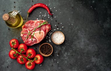 raw beef steak with tomatoes and spices on a stone background.