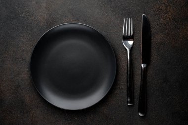 Siyah plaka, çatal ve bıçakla taştan bir arka planda