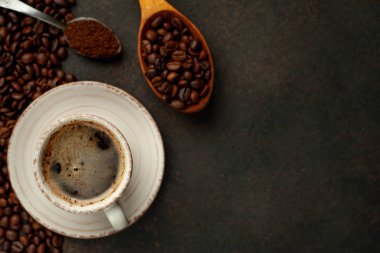 To view of cup of tasty coffee and beans on a stone background. 