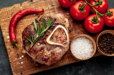 grilled steak, with tomatoes and spices on a stone background.