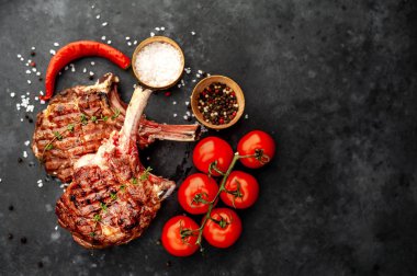 steak - grilled beef tomahawk with spices, thyme on a stone background