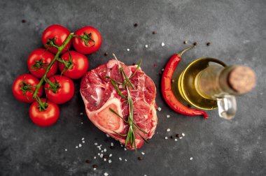 raw beef steak with tomatoes and spices on a stone background.