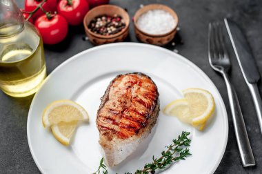 Grilled salmon steak in a white plate with spices on a stone background