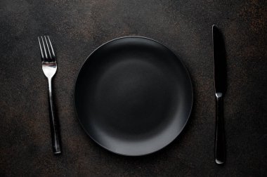 Siyah plaka, çatal ve bıçakla taştan bir arka planda