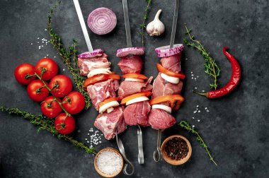 Çiğ et şişlerinin üst görüntüsü. Arka planda sebzeli ve baharatlı ızgara et..