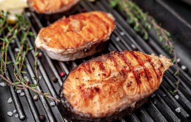 Grilled salmon steaks with on a grill pan with spices on a stone background with copy space for your background