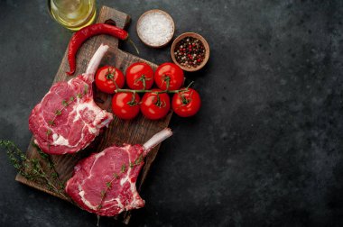İki çiğ biftek, baharatlı dana baltası, arka planda kekik.