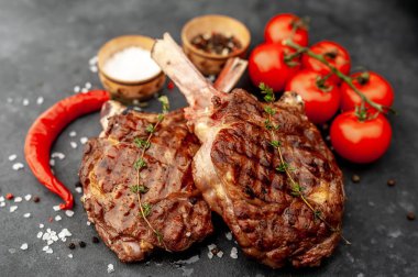 steak - grilled beef tomahawk with spices, thyme on a stone background