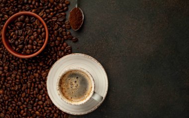 Top view of cup of tasty coffee and beans on a stone background with space for text 
