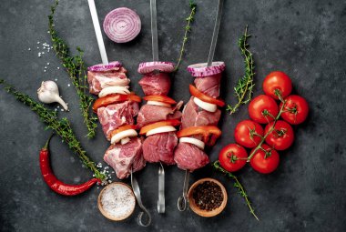 Çiğ et şişlerinin üst görüntüsü. Arka planda sebzeli ve baharatlı ızgara et..