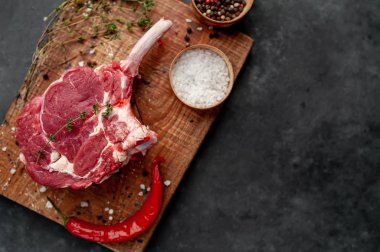 İki çiğ biftek, baharatlı dana baltası, arka planda kekik.