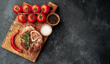 grilled steak, with tomatoes and spices on a stone background.
