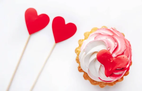 cake with drawings in the form of a heart and two hearts of red paper on a white background for Valentine\'s Day with copy space for your text