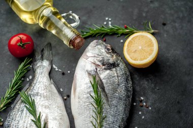 Baharatlı ve malzemeli taze dorado balığı domates, biberiye, ayçiçeği yağı, arkaplanda pişirmek için limon.