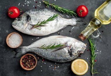 Baharatlı ve malzemeli taze dorado balığı domates, biberiye, ayçiçeği yağı, arkaplanda pişirmek için limon.