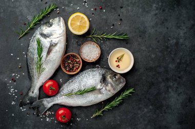 Baharatlı ve malzemeli taze dorado balığı domates, biberiye, ayçiçeği yağı, arkaplanda pişirmek için limon.