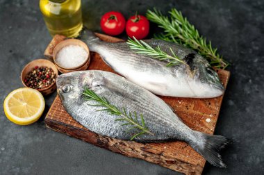 Baharatlı ve malzemeli taze dorado balığı domates, biberiye, ayçiçeği yağı, arkaplanda pişirmek için limon.