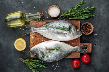 Baharatlı ve malzemeli taze dorado balığı domates, biberiye, ayçiçeği yağı, arkaplanda pişirmek için limon.