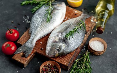 Baharatlı ve malzemeli taze dorado balığı domates, biberiye, ayçiçeği yağı, arkaplanda pişirmek için limon.