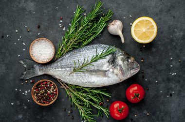 Baharatlı ve malzemeli taze dorado balığı domates, biberiye, ayçiçeği yağı, arkaplanda pişirmek için limon.