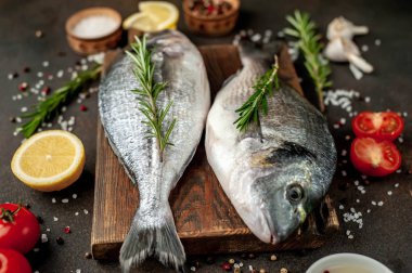 Baharatlı ve malzemeli taze dorado balığı domates, biberiye, ayçiçeği yağı, arkaplanda pişirmek için limon.