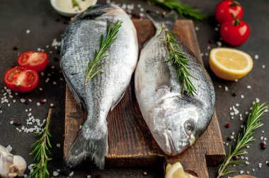 Baharatlı ve malzemeli taze dorado balığı domates, biberiye, ayçiçeği yağı, arkaplanda pişirmek için limon.