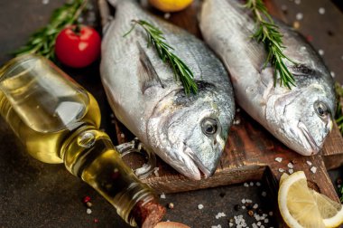 Baharatlı ve malzemeli taze dorado balığı domates, biberiye, ayçiçeği yağı, arkaplanda pişirmek için limon.