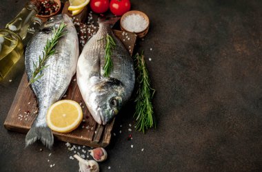 Baharatlı ve malzemeli taze dorado balığı domates, biberiye, ayçiçeği yağı, arkaplanda pişirmek için limon.