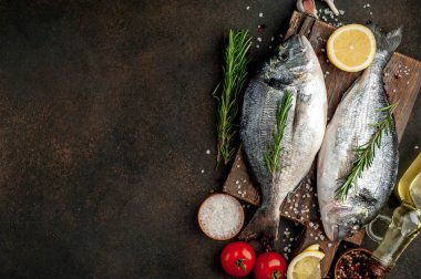 Baharatlı ve malzemeli taze dorado balığı domates, biberiye, ayçiçeği yağı, arkaplanda pişirmek için limon.