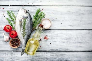 Baharatlı taze dorado balığı ve ahşap masa arkaplanında yemek pişirmek için gerekli malzemeler ve metin için fotokopi alanı.