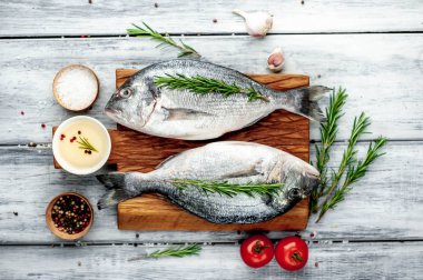 Baharatlı taze dorado balığı ve ahşap masa arkaplanında yemek pişirmek için gerekli malzemeler ve metin için fotokopi alanı.