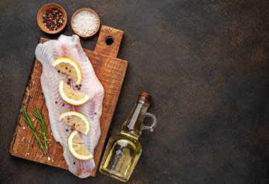 Limon, yağ ve baharatla dolu bir kesme tahtasındaki çiğ pangasius filetosu. 