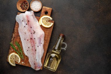 Limon, yağ ve baharatla dolu bir kesme tahtasındaki çiğ pangasius filetosu. 