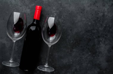 Bir şişe kırmızı şarap ve arka planda şarap olan bir bardak. Kopyalama alanı olan üst görünüm