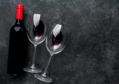 Bir şişe kırmızı şarap ve arka planda şarap olan bir bardak. Kopyalama alanı olan üst görünüm