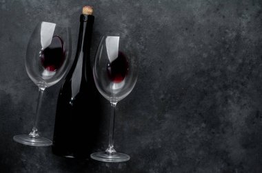 Bir şişe kırmızı şarap ve arka planda şarap olan bir bardak. Kopyalama alanı olan üst görünüm