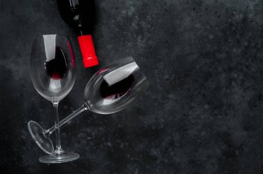 Bir şişe kırmızı şarap ve arka planda şarap olan bir bardak. Kopyalama alanı olan üst görünüm