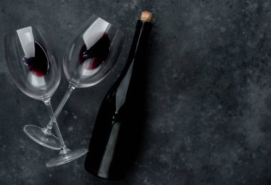 Bir şişe kırmızı şarap ve arka planda şarap olan bir bardak. Kopyalama alanı olan üst görünüm
