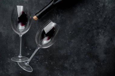 Bir şişe kırmızı şarap ve arka planda şarap olan bir bardak. Kopyalama alanı olan üst görünüm
