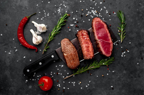 Three pieces of meat grilled over a meat knife Three types of frying meat, rare, medium, well done on stone background with copy space for your text