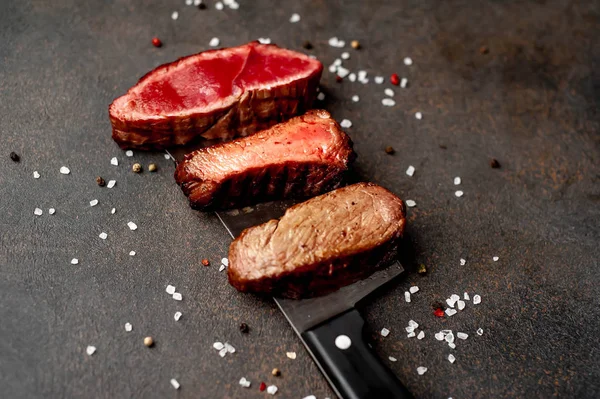 Three pieces of meat grilled over a meat knife Three types of frying meat, rare, medium, well done on stone background with copy space for your text