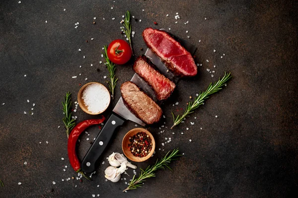 Three pieces of meat grilled over a meat knife Three types of frying meat, rare, medium, well done on stone background with copy space for your text