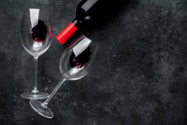 Bir şişe kırmızı şarap ve arka planda şarap olan bir bardak. Kopyalama alanı olan üst görünüm