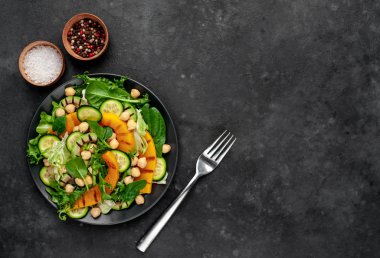 plate of avocado salad, chickpeas, pumpkins, cucumbers, poached eggs in plate on stone background